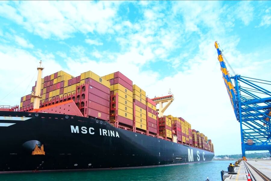 Container ship loaded with containers beside quay cranes